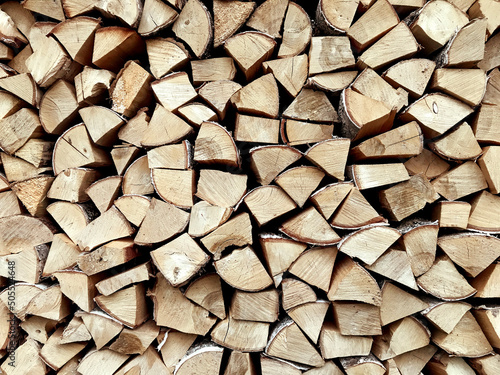 Woodpile folded  on one another in countryside  horizontal  background wooden wall texture. Preparation for winter  natural fuel  green energy  dry wood for fireplace  timber and logs  close up