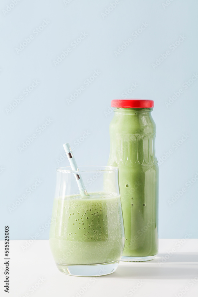 healthy green smoothie in glass, bottle with straw on blue background. Vegetarian healthy lifestyle concept.refreshing drink. quick snack. copy space healthy green smoothie in glass, bottle with straw on blue background. Vegetarian healthy lifestyle concept.refreshing drink. quick snack. copy space