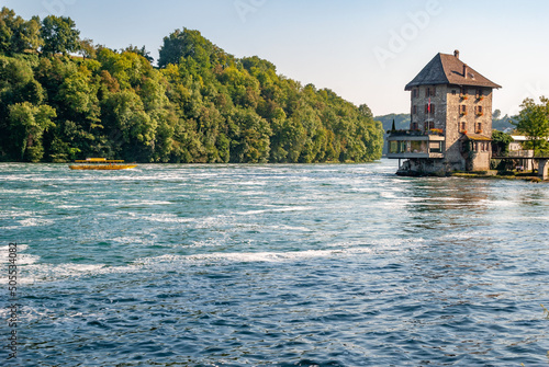 Natural view of rushing Rheinfall river and an old buildingd in Schaffhausen, Switzerland photo