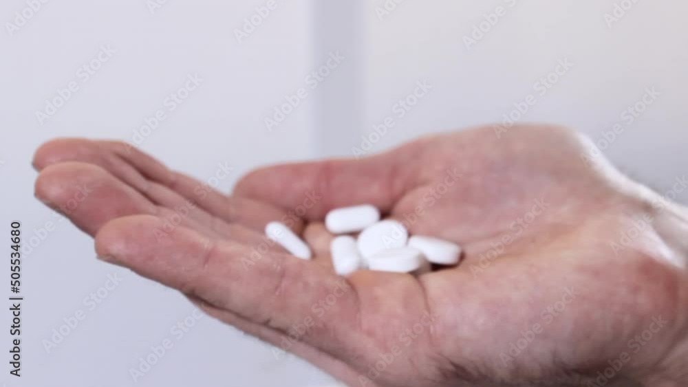 Adult male taking medication. Hand holding white tablets. Big dosage therapy Adult male taking medication. Hand holding white tablets. Big dosage therapy
