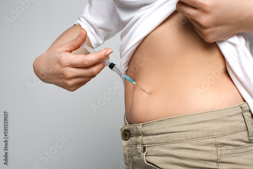фотографія Studio close up of blonde caucasian woman holding needle making self injection i