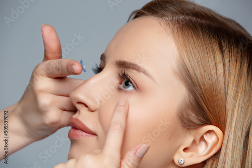 Close up woman putting eye contact lense in or taking out, holding on finger. Eye disorder treatment like myopia or nearsightedness, astigmatism or cosmetic lenses. Vision improvement and correction.