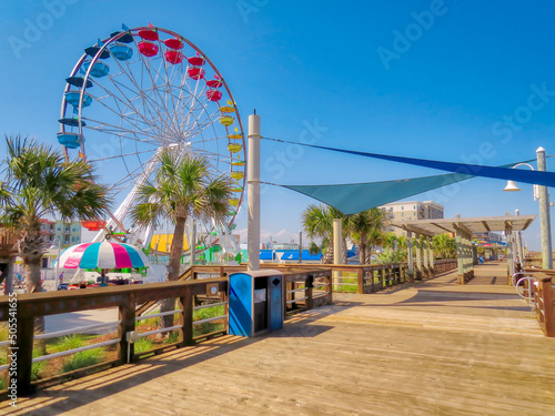 Fototapeta A large, colorful Ferris wheel at the Carolina Beach boardwalk in North Carolina under a blue sky
