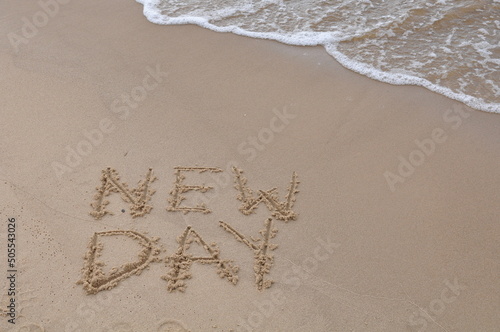 New Day words - drawing on the sand, handwritten on the sea beach sand