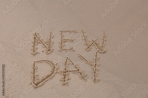 New Day words - drawing on the sand, handwritten on the sea beach sand