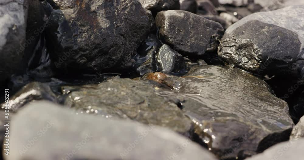 A small stream flowing inbetween rocks at the Tustumena glacier in Kenai, Alaska A small stream flowing inbetween rocks at the Tustumena glacier in Kenai, Alaska