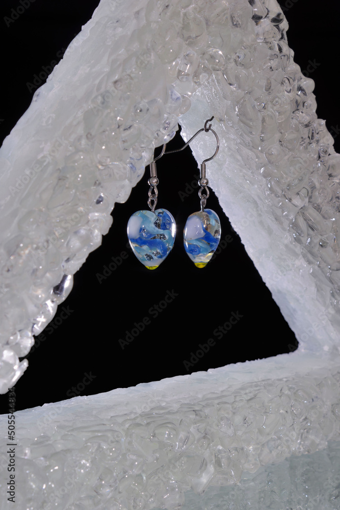 Φωτογραφία Closeup shot of the handmade glass earrings hanging on a jewelry holder on a bla