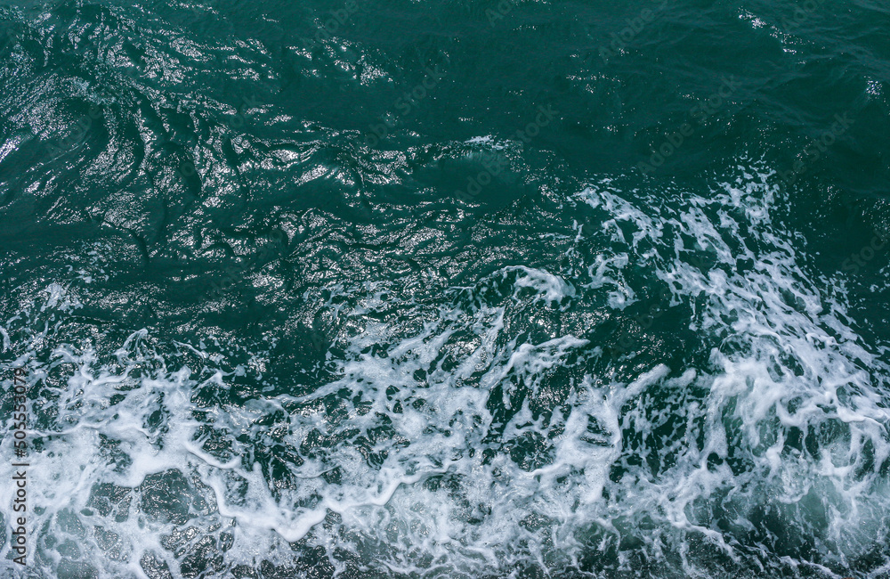 Beautiful sea waves with foam of blue and turquoise color. Abstract blue sea water with white wave. Blue and white waves of the ship road on the water sea ocean. Beautiful sea waves with foam of blue and turquoise color. Abstract blue sea water with white wave. Blue and white waves of the ship road on the water sea ocean.