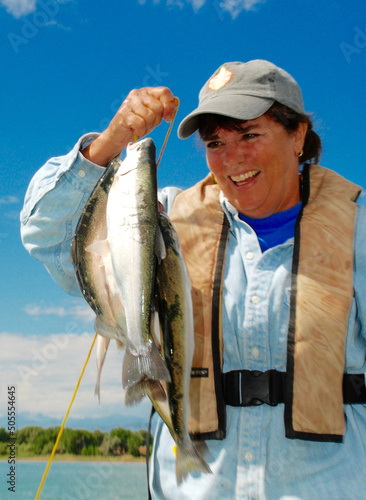 A female angler with a stringer of trout and walleye 