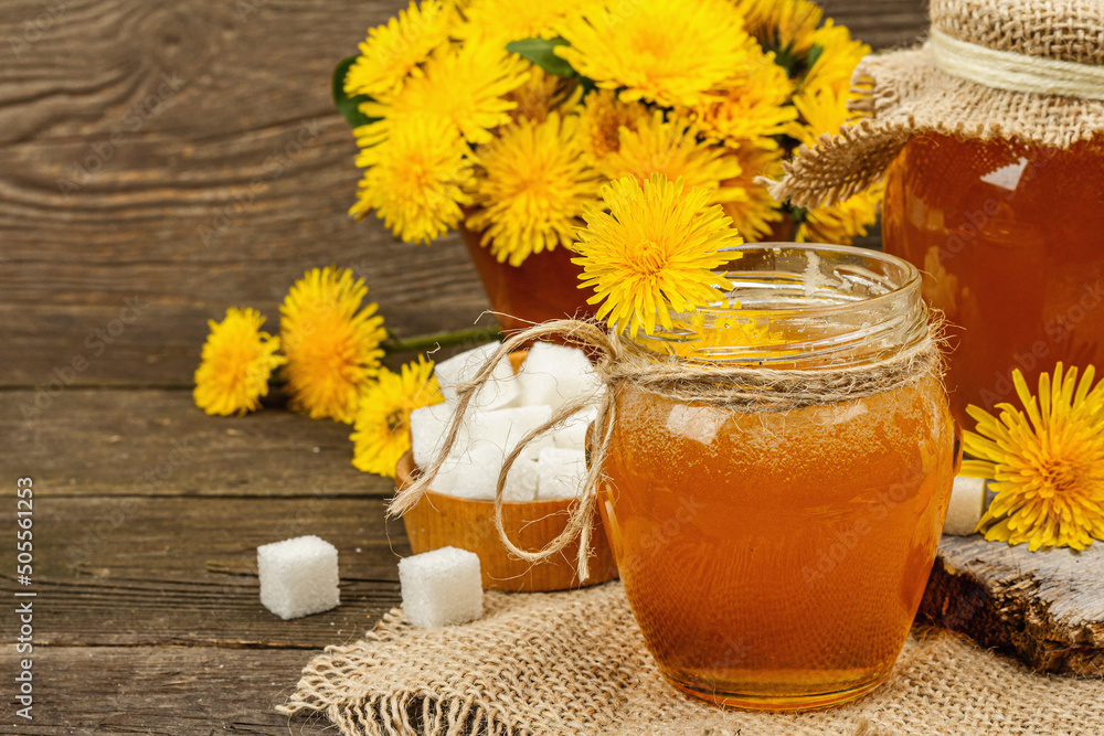Dandelion jam or honey in the glass jar with a bouquet of fresh blooming dandelion flowers