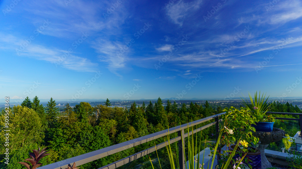 Panoramic summer view of BC Lower Mainland with Straits of Georgia and Gulf Islands on far horizon as seen from a Burnaby Mountain rooftop patio garden.
