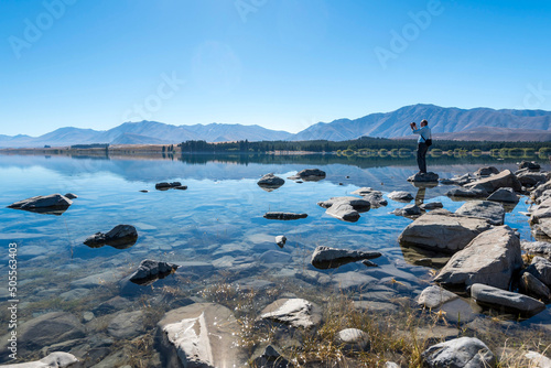 Male traveler photographs the beautiful landscape of Lake Tekapo, New Zealand.