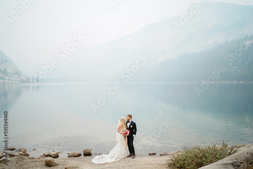 Couple romantically posing at elopement in foggy misty mountain lake photo