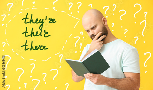 Thoughtful man studying English grammar on yellow background photo
