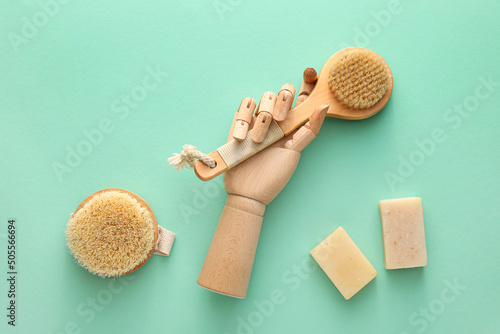 Wooden hand with massage brushes and soap on turquoise background