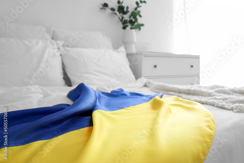 Flag of Ukraine on modern bed in light room, closeup © Pixel-Shot