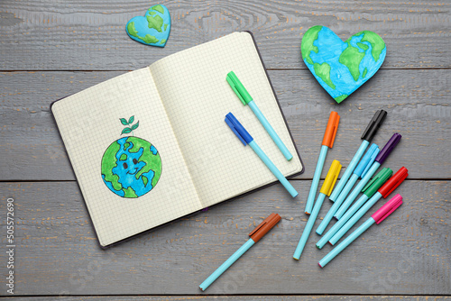 Happy Earth Day. Flat lay composition with notebook and markers on grey wooden table photo