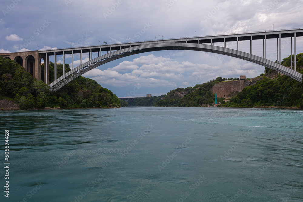 Obraz premium Niagara Falls, Canada - August 27, 2021: The Rainbow Bridge at Niagara Falls is a steel arch bridge that spans the Niagara Gorge. She connects Ontario, Canada and New York, United States.