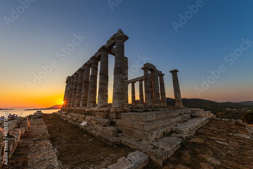 Amazing colorful sunset at the Temple of Poseidon, archaeological site of Sounion, Attica. Cape Sounion, Lavrio, Greece. A sunset behind the citadel on a hill at the shoreline of Mediterranean Sea.