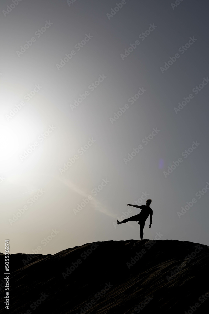Silhouette at sunset of a man doing silly poses