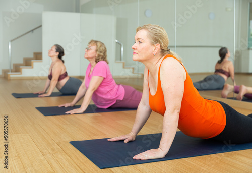 Mature women practicing yoga training - pose bhujangasana