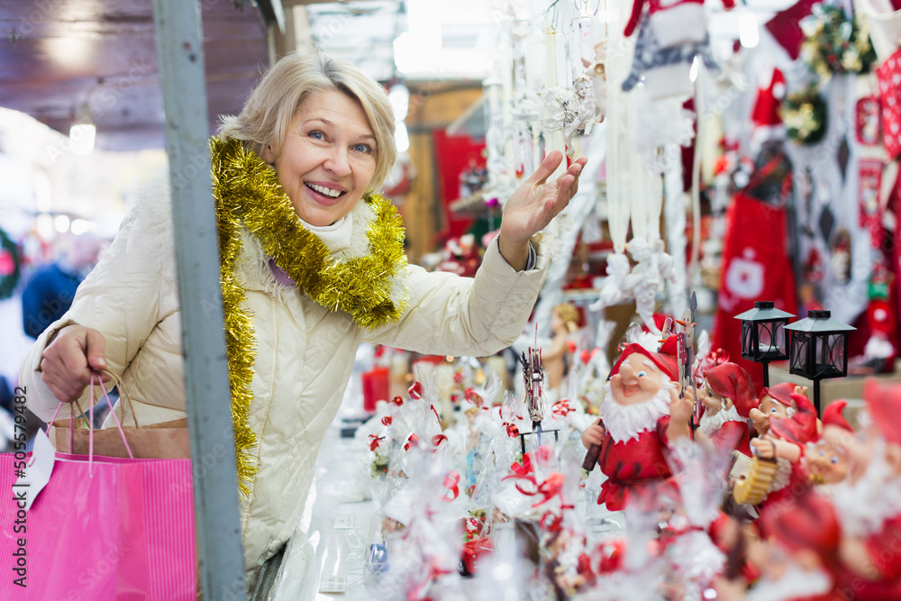 Adult woman is choosing Christmas decorations for house in the market outdoor.