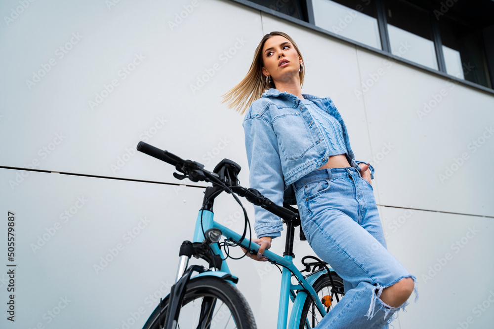 Vogue style shot of pretty blonde girl hair, flying standing with blue  electric bike. Young modern city girl Stock Photo | Adobe Stock