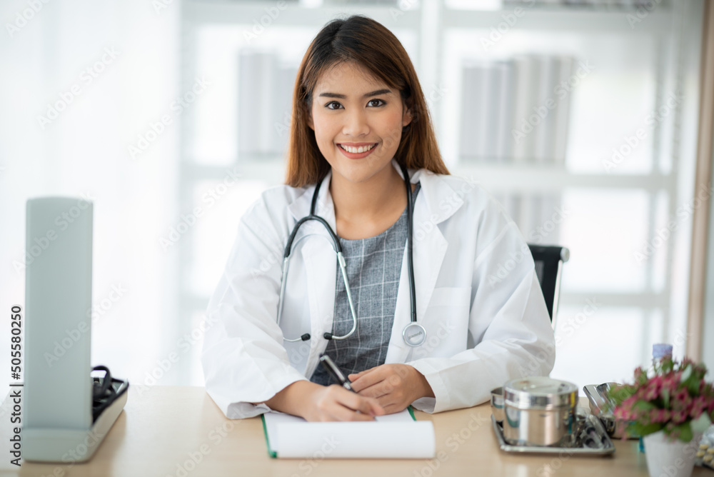 Portrait of smiling and successful young female doctor and specialist physician with stethoscope around neck and wearing labcoat standing with crossed arms in hospital Portrait of smiling and successful young female doctor and specialist physician with stethoscope around neck and wearing labcoat standing with crossed arms in hospital