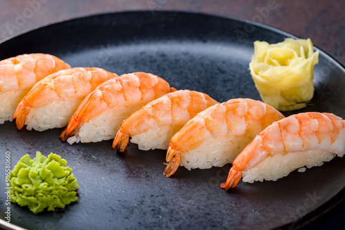 sushi with shrimp on a black plate on blue concrete table macro close up photo