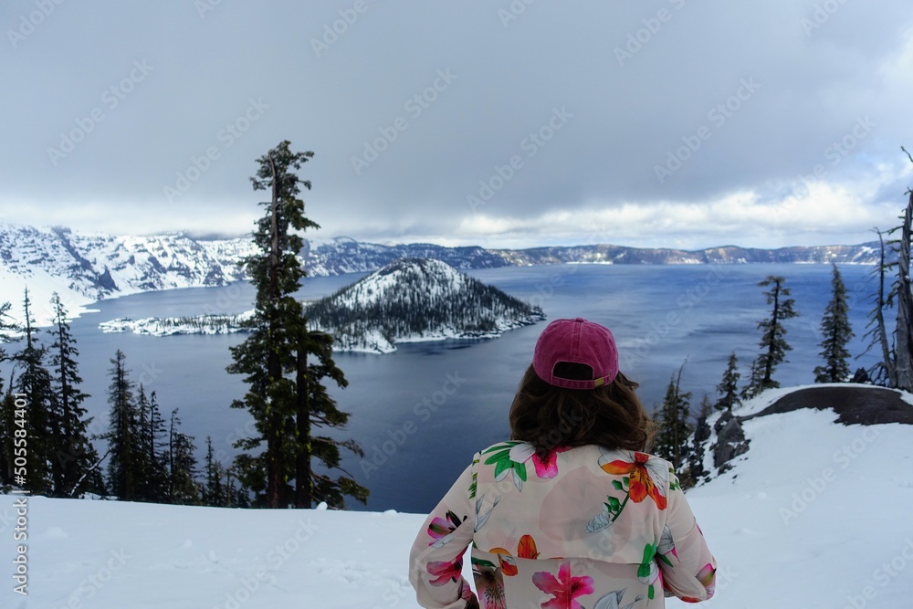 A young woman admiring the beautiful lookout view of crater lake, in crater lake national park, Oregon, United states. 