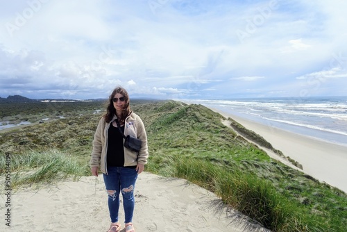 A young woman admiring the Beautiful views of the oregon coast with it's vast sandy beaches and endless sandy dunes, on a sunny blue sky day