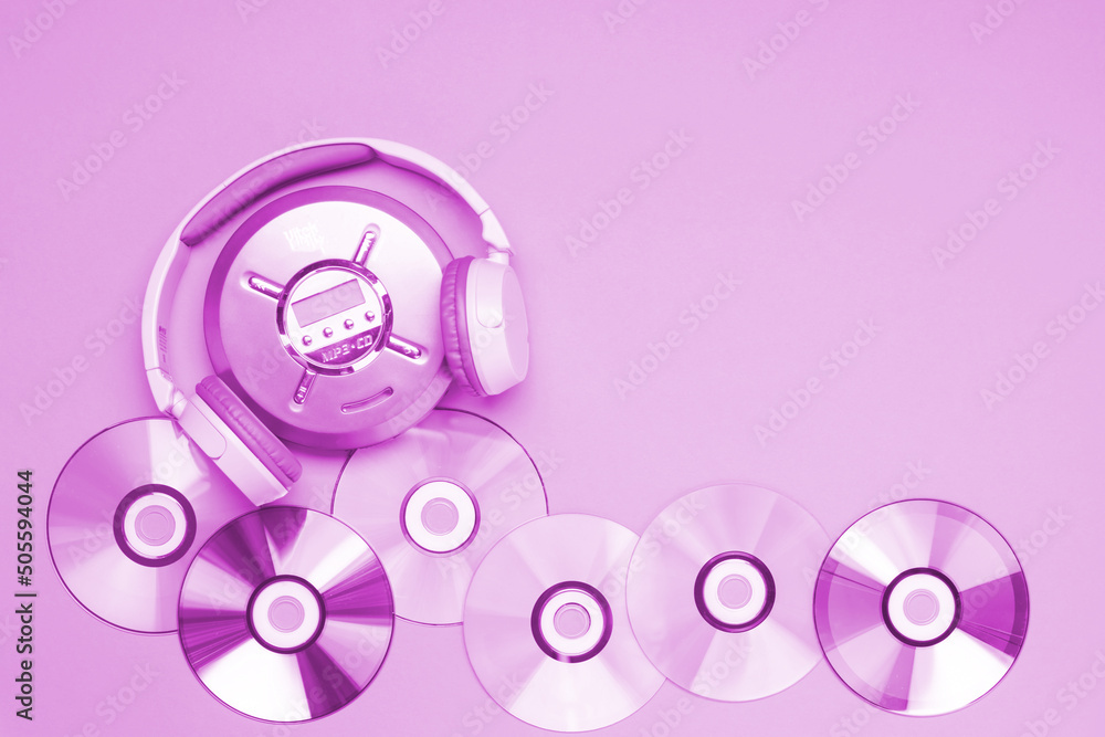 Personal compact portable CD player disks purple headphones on a pink background. Personal compact portable CD player disks purple headphones on a pink background.