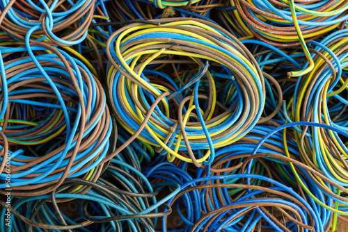 Colorful, coiled copper cables in rubber sheaths. Prepared for further recycling, copper recovery. Cables texture in full screen