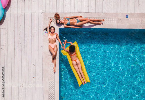 Fotografia Friends in swimsuit who tan in the sunbed in a swimming pool