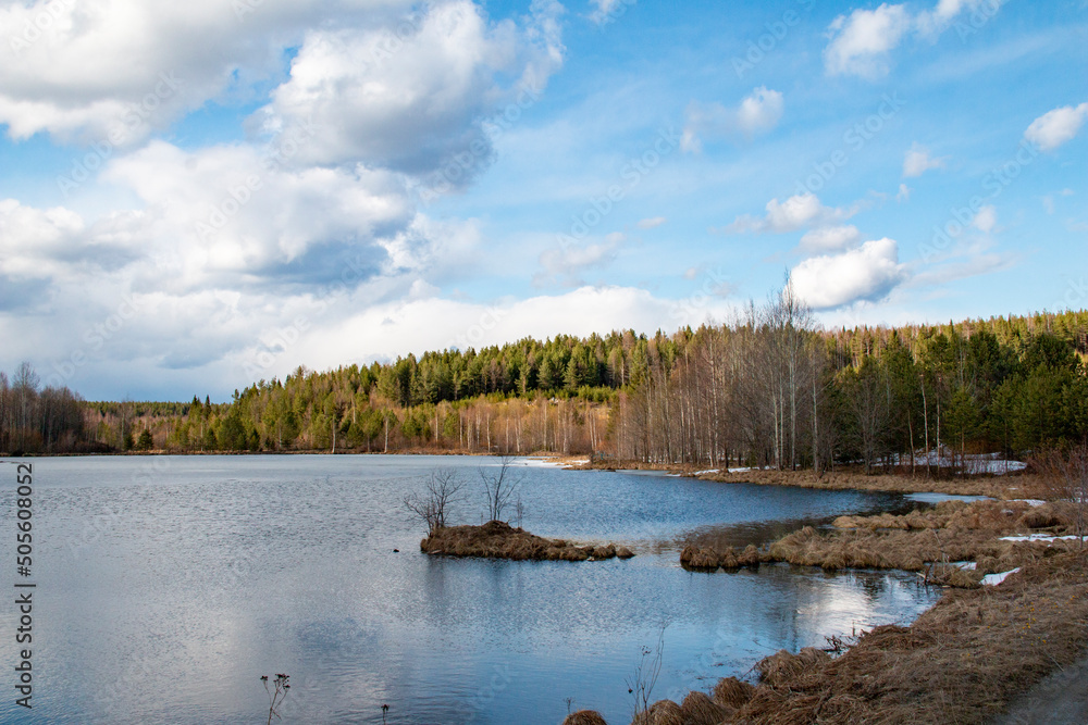 Quarry, rocks and lake in spring. Landscape in the Sverdlovsk region with spring melting snow, streams and a lake.