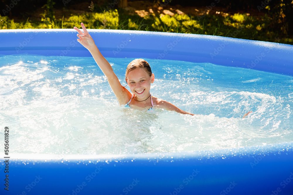 A child in the water. A girl splashes in an inflatable pool in the garden on a sunny summer day.