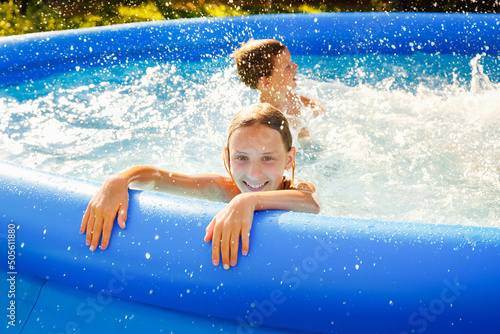 Summer season concept background. Happy friends in an inflatable pool in the garden, refreshing themselves in hot weather.