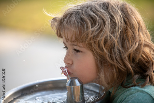 Close up portrait of kid boy drinking water from outdoor water fountain outdoor.
