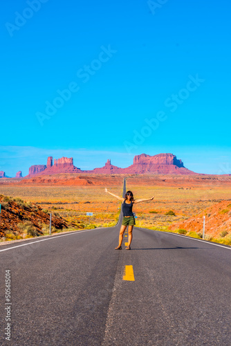 A young woman in a black T-shirt sitting on the road to Monument Valley. Utah