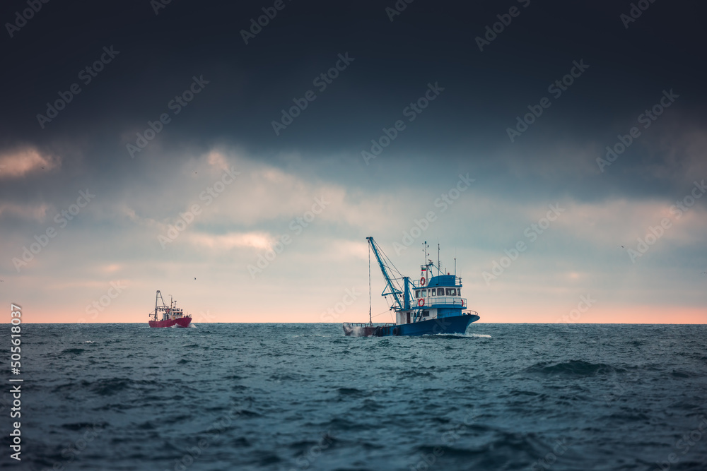 Fishing boat and fisherman in the sea, foggy morning over the water