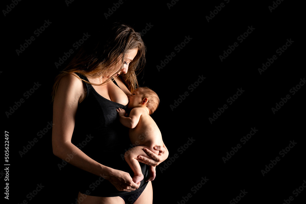 Naklejka premium Young mother in the studio breastfeeding her newborn baby