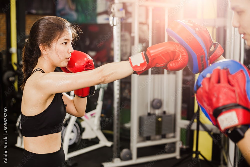 Asian female boxer training Punch to the target of the trainer. Asian female boxer training Punch to the target of the trainer.