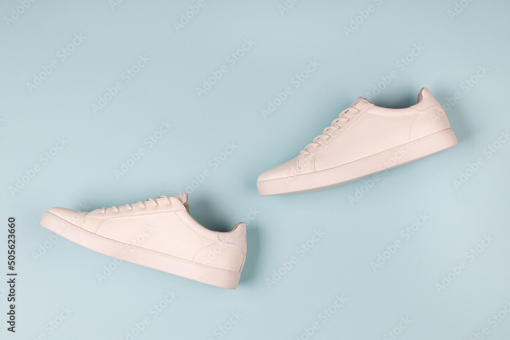 Pair of new white sneakers on blue background Pair of new white sneakers on blue background