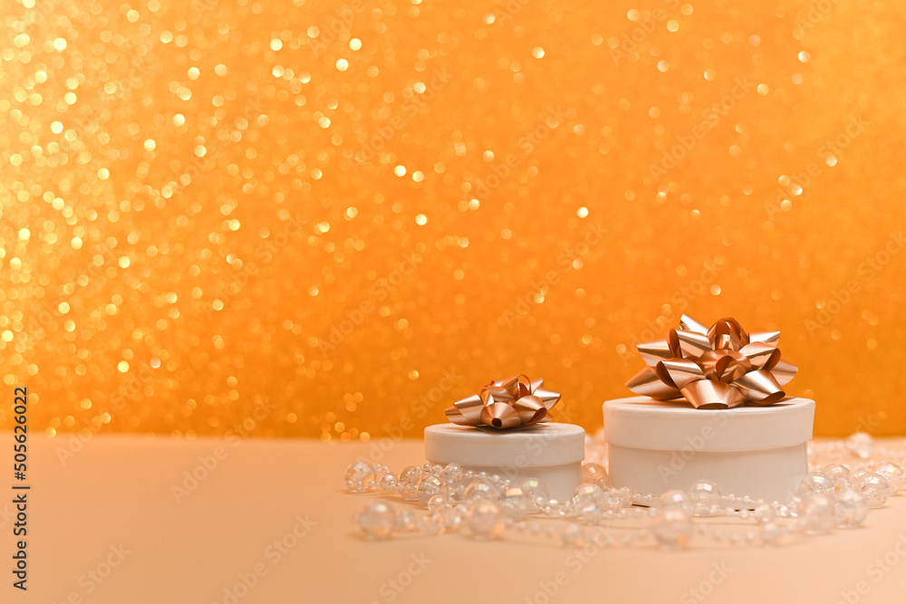 Round gift boxes with bows on top, on an abstract golden blurred bokeh background. Selective focusing and shallow depth of field. A holiday card. Round gift boxes with bows on top, on an abstract golden blurred bokeh background. Selective focusing and shallow depth of field. A holiday card.