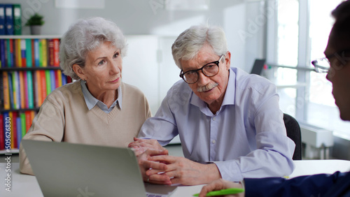 Insurance agent advising elderly couple about savings