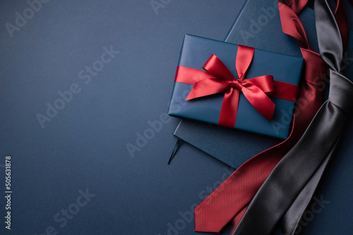 Fotografia Blue gift box, notebook and neckties on dark blue background.