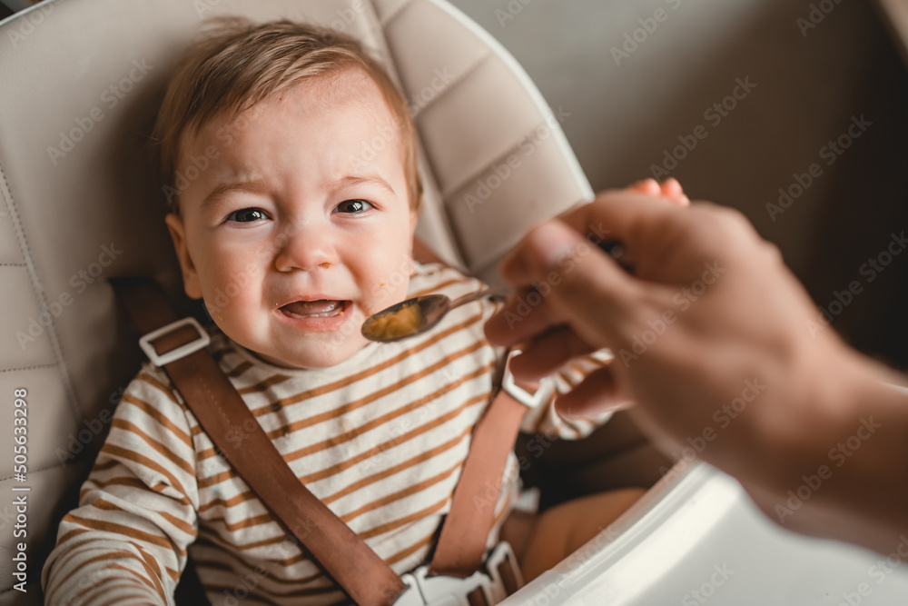 Φωτογραφία Toddler crying at lunch time sitting in a highchair in the living room at home