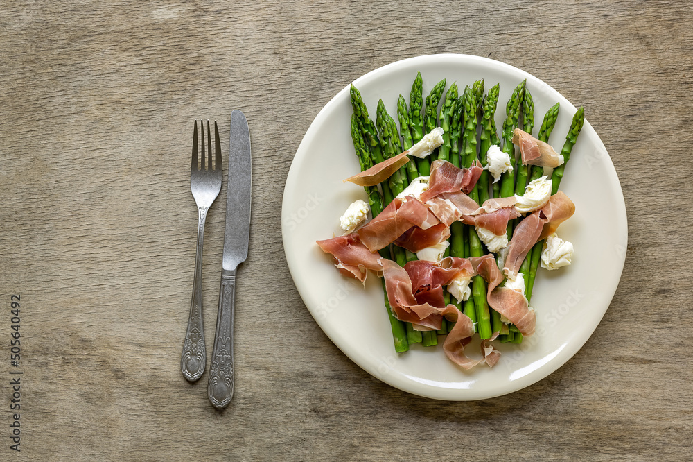 Plate with green asparagus with mozzarella cheese and prosciutto ham Plate with green asparagus with mozzarella cheese and prosciutto ham