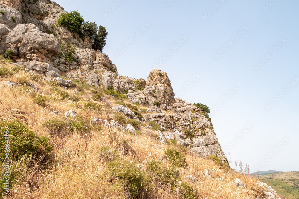 Overgrown  with small crooked trees, grass and bushes, the slope of Mount Arbel, located on the shores of Lake Kinneret - the Sea of Galilee, near the city of Tiberias, in northern Israel.