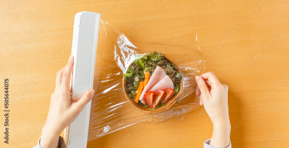 Woman preserving salad with cling wrap for foods. Preserve food, keep fresh, etc. 食品用保存のラップを用いてサラダを保存する女性。食品保存、鮮度を保つなど - obrazy, fototapety, plakaty 
